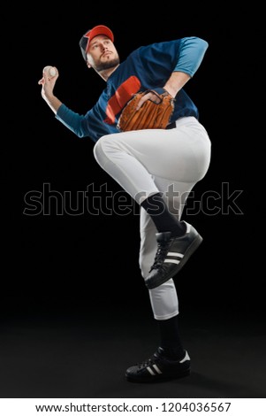 Baseball player in a wind up position on black background. Adult skilled pitcher throwing a ball.