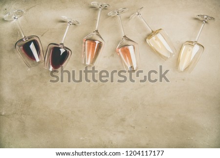 Flat-lay of red, rose and white wine in glasses and corkscrews over grey concrete background, top view, copy space. Wine bar, winery, wine degustation concept