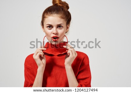 woman in red sweater holds sunglasses                           