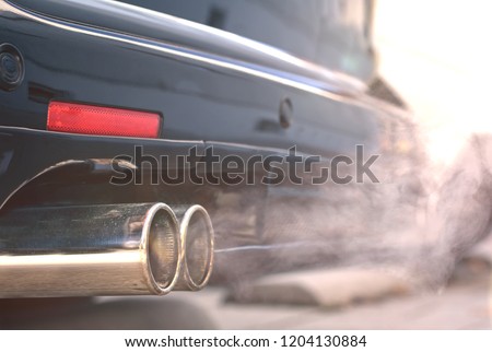 Close up of smoky dual exhaust pipes from a starting diesel car - emissions scandal. Royalty-Free Stock Photo #1204130884