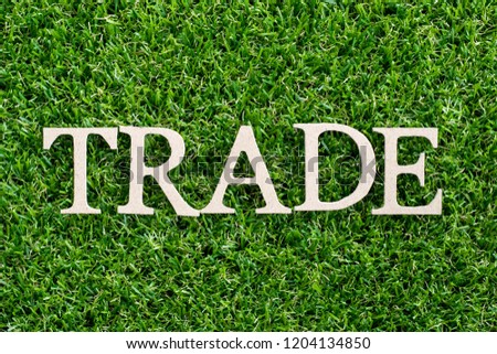 Wood letter in word trade on artificial green grass background