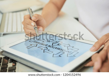 Faceless shot of woman holding touchpad showing image of information streams sitting at desk