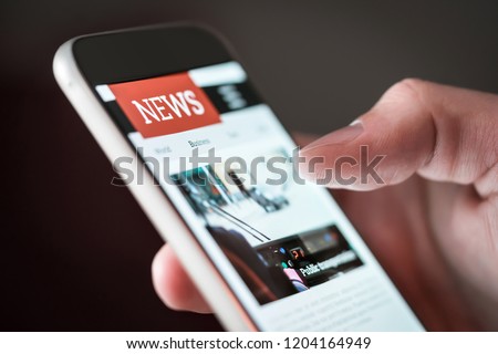 Mobile news application in smartphone. Man reading online news on website with cellphone. Person browsing latest articles on the internet. Light from phone screen. Royalty-Free Stock Photo #1204164949