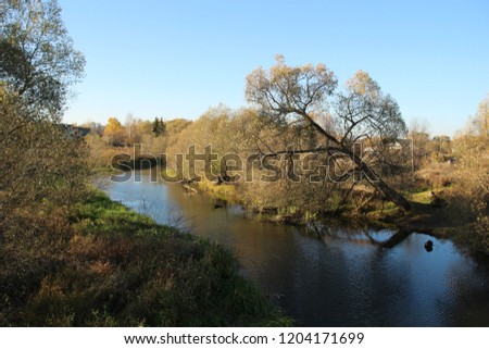 Beautiful countryside landscape with river and colorful autumn trees in sunny day