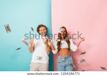 Excited young couple isolated over double colored background, standing under money banknotes shower, celebrating