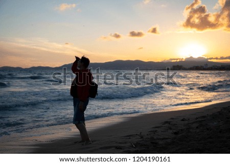 Older woman looking out to sea and enjoying beautiful sunset on a beach.