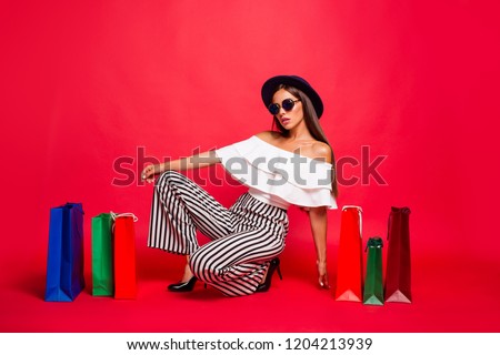 Nice attractive trendy stylish elegant lady wearing eyeglasses eyewear off-the-shoulders ruffles blouse top high heels shoes sitting among colorful bags leisure isolated on red pastel background