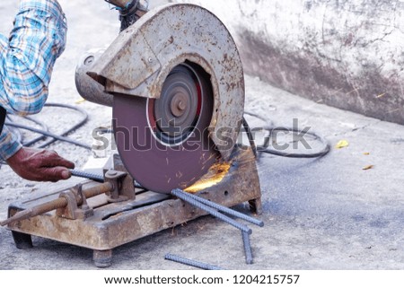 Worker cutting steel with an industrial Fiber cutter for job in workshop.