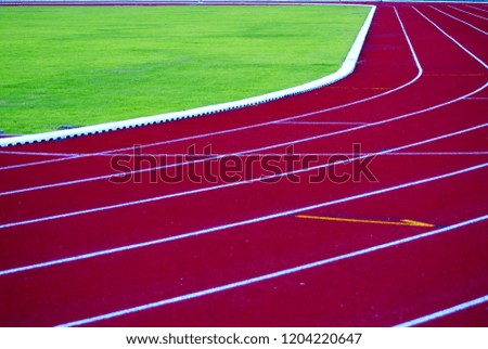 Selective focus picture line of running track lanes around green grass field for jogging