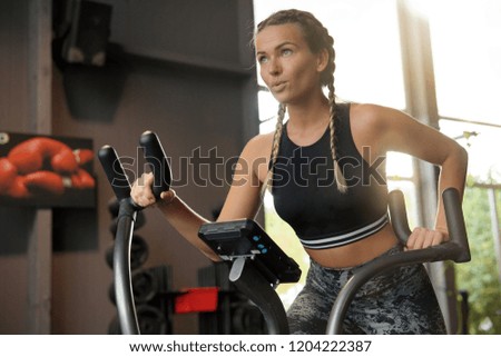  Woman in a gym working out on an air bike                              