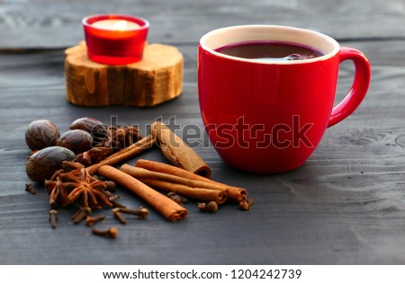 Christmas mulled wine with spices in red mug on wooden background. Cinnamon, nutmeg, star anise, cloves.