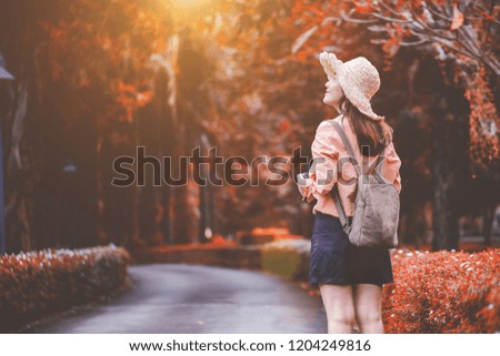 Smiling woman traveler enjoying travel in natural in the park on Autumn on vacation.