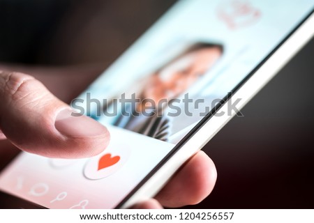 Dating app or site in mobile phone screen. Man swiping and liking profiles on relationship site or application. Single guy using smartphone to find love, partner and girlfriend. Mockup website. Royalty-Free Stock Photo #1204256557