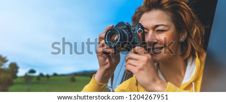 smile tourist girl in an open window of a auto car taking photography click on retro vintage photo camera, photographer looking on camera technology, blogger using hobby content concept, enjoy trip