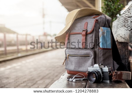 Image backpack, Mobile phone, earphone, map, hat and camera film on floor at the train station. Travel concept. vintage style.