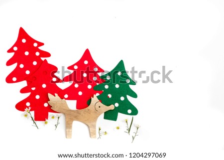 A little wooden fox with tiny white flowers and green and red pine trees background. Holidays concept.