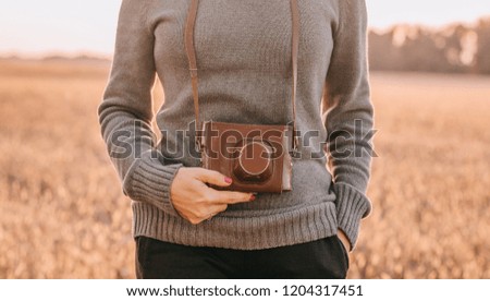 a girl with a vintage photocamera in a gray knit sweater on autumn background