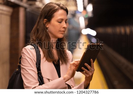 Business woman in city using tablet computer at subway platform