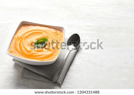Bowl of tasty pumpkin soup on light background. Space for text