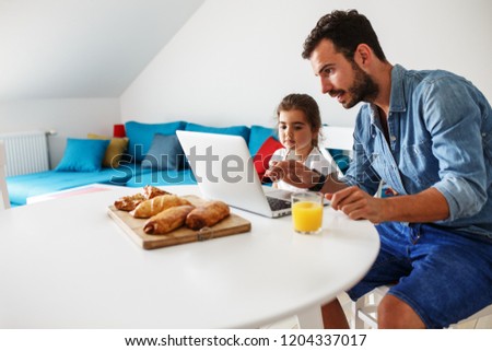 Family breakfast.Father with his daughter sitting at the table and watching cartoons on laptop.