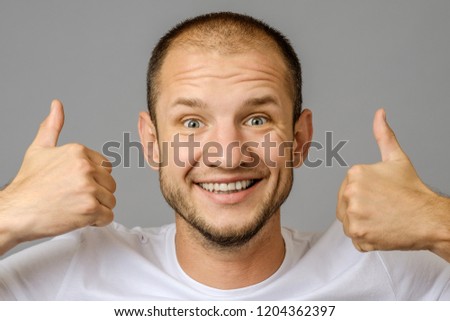 Portrait of man smiling and showing two thumbs up on gray background