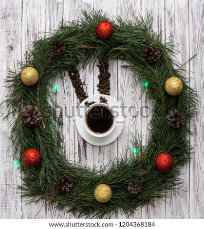 Christmas clock made of fir branches, clock hands of pine nuts, a cup of coffee and Christmas toys on a white wooden background, clock