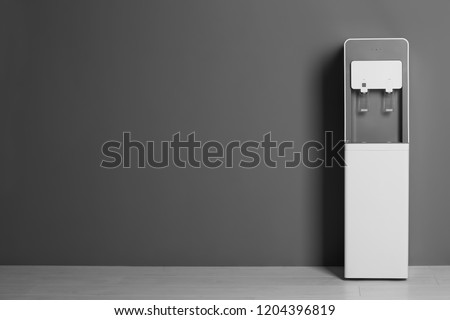 Modern water cooler against gray wall with space for text Royalty-Free Stock Photo #1204396819