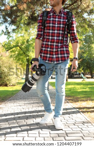 Young male photographer with professional camera in park