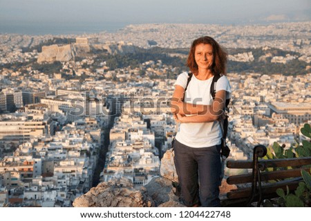 woman sitting on Lycabettus Hill, the highest point in the city overlooking Athens with the Acropolis - world traveller