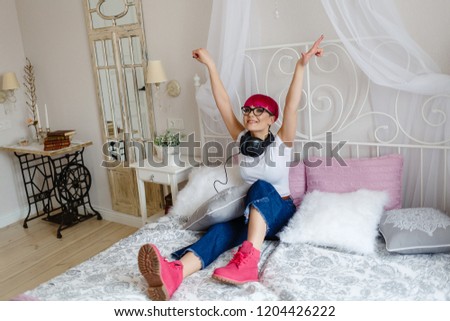 girl with pink hair listens to music and rests on the bed
