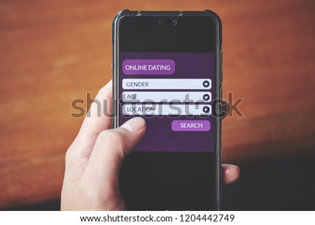 Online dating concept. Male hands using smart phone to find matching partner on dating application website on the screen. Front view and close up photo. All screen graphics are made up with own design