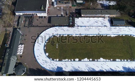 Aerial picture of oval shaped ice rink a frozen body of water where people are enjoying winter sports ice-skating this track is mechanically where coolant produces cold temperatures in surface below
