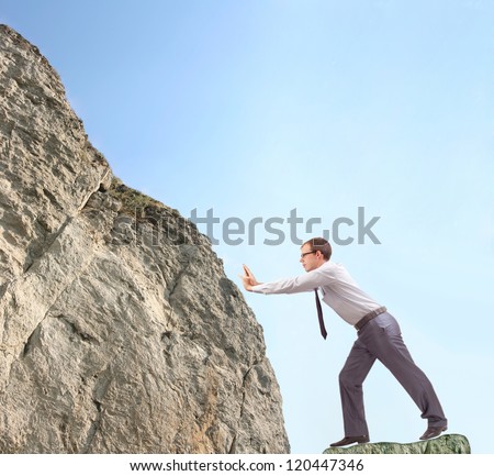 businessman pushing uphill a heavy stone - Symbol of the difficulties leader, hard work, hard to the effort