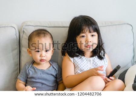 Little baby boy and little girl sister watching cartoon TV together at home and having fun together.Family with children at home.