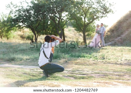 wedding photographer takes pictures of bride and groom in nature. wedding couple on photo shoot. photographer in action