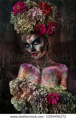 close up portrait of young beautiful girl with Halloween professional makeup. girl with skull makeup and with flower crown on head. bright face art. Halloween pumpkin. Mexican death