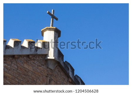 A Christian background image featuring a stone cross isolated on a blue sky. This image can be used to represent Christianity or religion. 