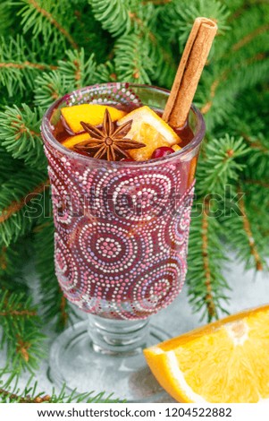 Traditional Christmas mulled red wine with spices (cinnamon, star anise, cardamom) and fruits (citrus, cranberry, apples) on grey concrete background. Delicious hot drink for New year. Selective focus