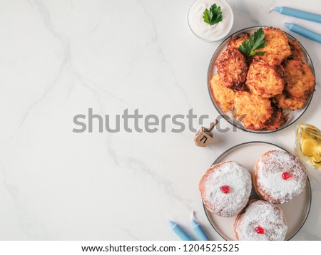 Jewish holiday Hanukkah concept and background. Hanukkah food, oil, candles and traditional spinnig dreidl. Top view or flat lay. Copy space for text.