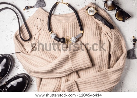 Women fashion cloth and accessories. Trendy Cozy Jumper. Flat lay. Vanilla Pastel colors and black accessories