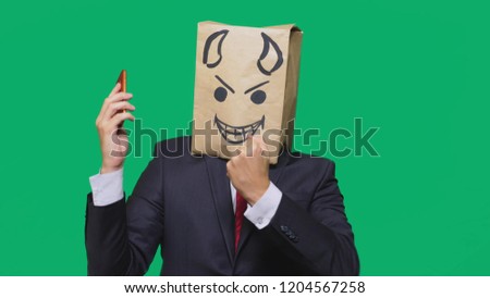 concept of emotions, gestures. a man with a package on his head, with a painted black smiley face, a devil, crafty, gloating, talking on a mobile phone.
