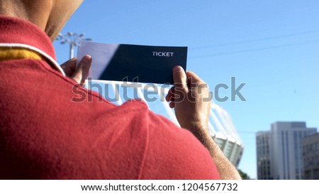 Happy man looking at football ticket, lucky lottery winner, excited before match