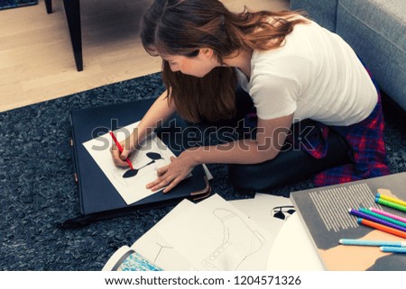 Female fashion designer working on new project and drawing on the paper. 