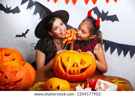 Mother and daughter having fun at home. Happy family preparing for Halloween. People wearing carnival costumes.