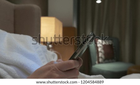 Closeup of young woman hands typing sms scrolling phone pictures. female hands use a smartphone in the evening on the bed