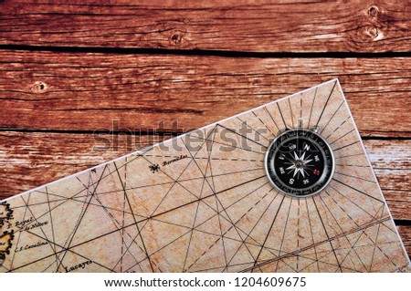 Compass with maps on top of wooden table