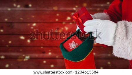 Digital composite of Santa putting gifts in stocking with red wood