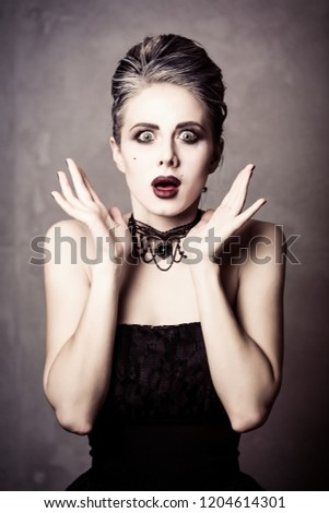Portrait of young woman in witch halloween costume and makeup on grey background