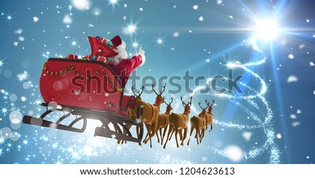 Digital composite of Santa flying in sleigh with Christmas sky