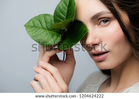 Beautiful girl with a green leaf in their hands